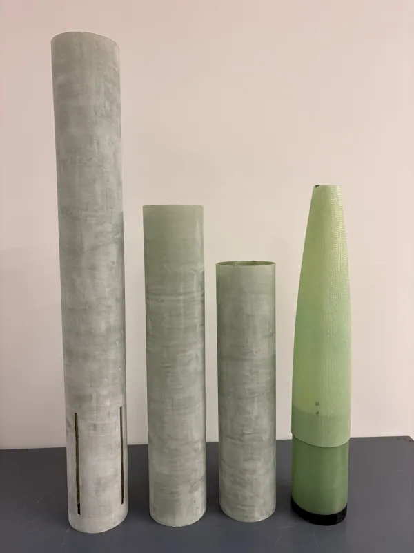 Three fibreglass tubes and a nose-cone component arranged upright