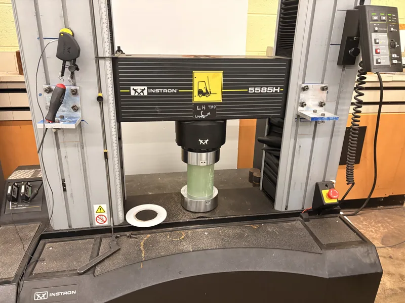 Tube specimen between the platens of an Instron test machine